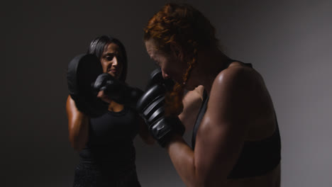 Studioaufnahme-Von-Zwei-Reifen-Frauen-In-Fitnesskleidung,-Die-Gemeinsam-Boxen-Und-Sparring-Trainieren-3